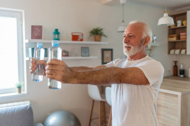 istock Senior man is exercising at home and using water bottles instead of weights. 1504040597