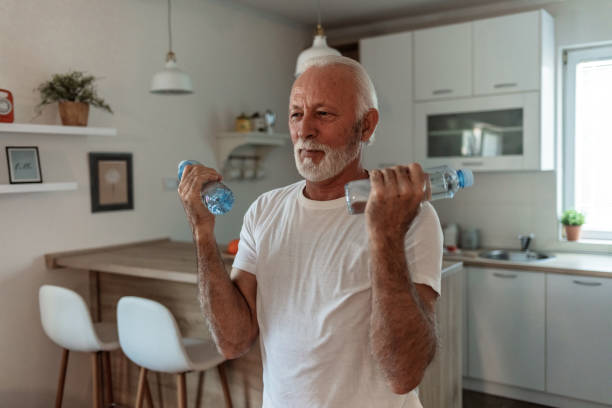 Elder man using bottle of water for home workout.