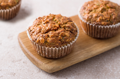 Homemade freshly baked pumpkin muffins with oatmeal and nuts on a beige textured background
