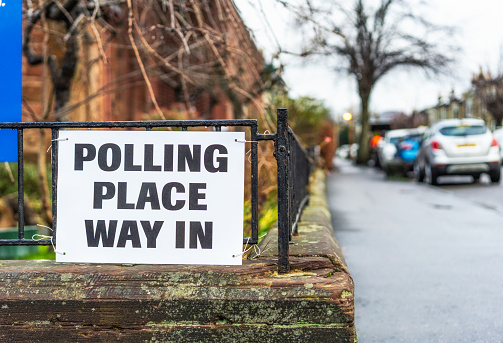 A sign on a pavement of a street in Glasgow, indicating a polling place for an election.