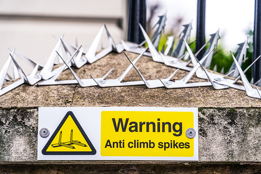 Large metal spikes to secure a building, with a sign warning people about them in London, UK.