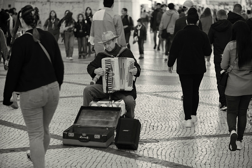 Lisbon, Portugal - December 17, 2022: A street musician plays an accordion at the Rua Augusta street in Lisbon downtown.