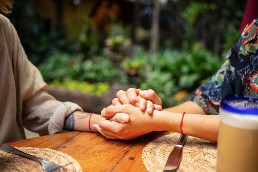 Close up of young couple sitting at the restaurant holding hands
