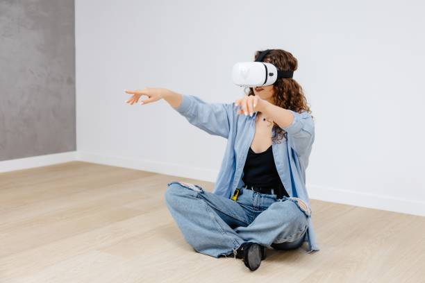 istock Young woman in VR glasses using modern technology creating room design, moving hands in air, standing in new apartment during renovation. Virtual reality and repair concept 1504088655