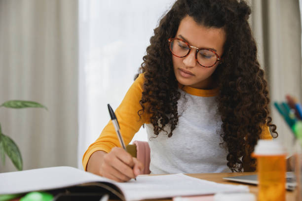 istock Student sitting at her desk with pills infront of her 1504092753