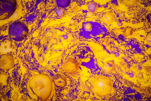 A close-up of a vibrant blend of purple and gold paint, creating a mesmerizing swirl of colors