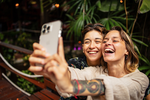 Same sex couple is sitting and taking photo with mobile phone