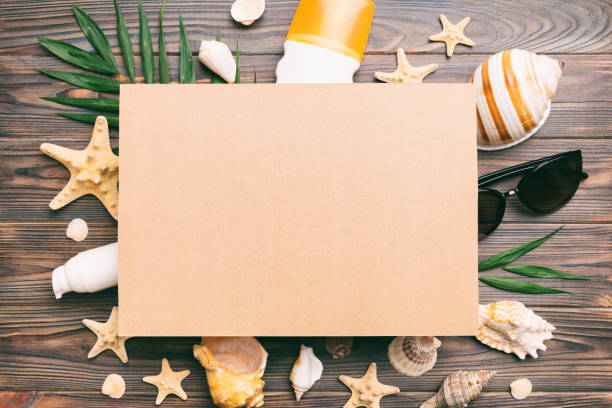 istock Summer time concept with blank greeting card and blank craft paper on colored background. Seashells from ocean shore in the shape of frame separated with space for text top view 1504100020