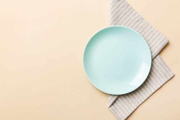 istock Top view on colored background empty round blue plate on tablecloth for food. Empty dish on napkin with space for your design 1504100045