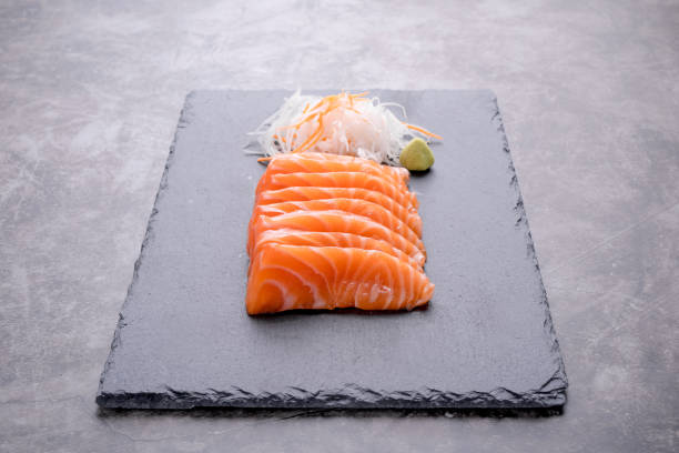 The salmon sashimi was laid out on a black stone plate