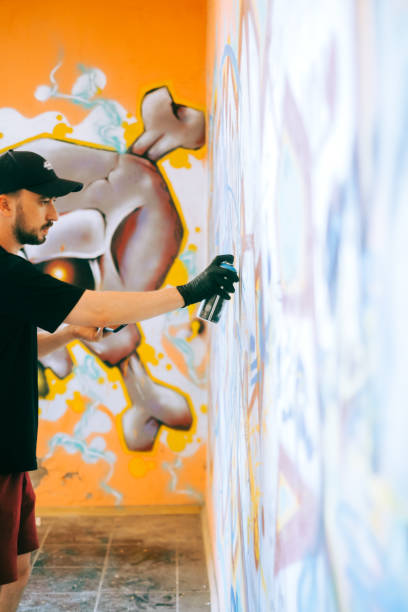 istock Young caucasian man graffiti artist drawing on a wall. 1504132068