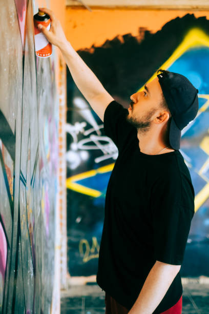 istock Young caucasian man graffiti artist drawing on a wall. 1504132142