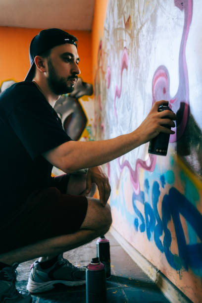 istock Young caucasian man graffiti artist drawing on a wall. 1504132809