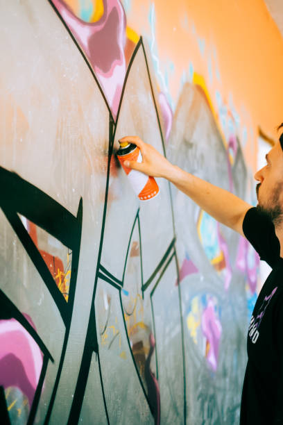istock Young caucasian man graffiti artist drawing on a wall. 1504132833