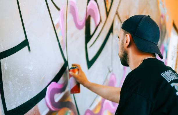 istock Young caucasian man graffiti artist drawing on a wall. 1504133446