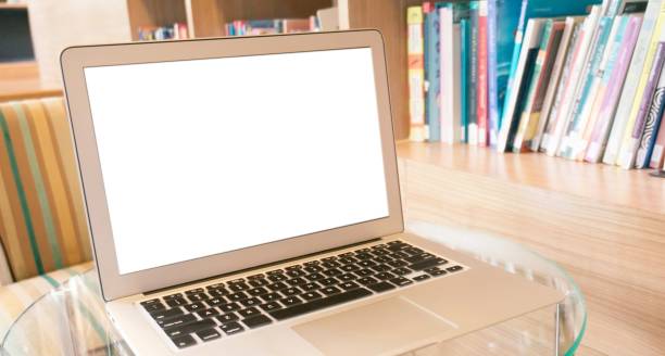 istock Laptop with blank screen on wooden table in front of library - technology concept 1504138914
