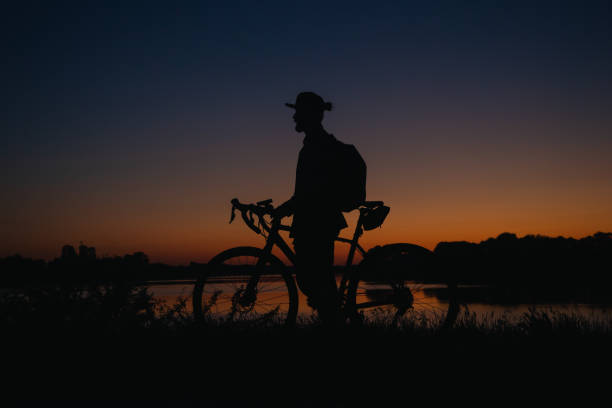 istock Silhouette of a man with a bicycle enjoying the sunset. 1504164236