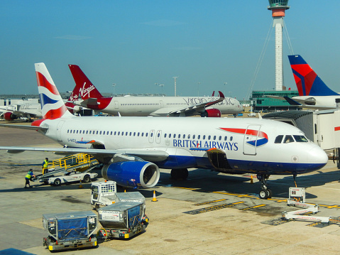 London, England, UK - 14 June 2023: British Airways Airbus A320 (registration G-MIDX) at a London airport. In the foreground are air freight pallets.