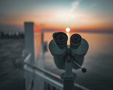 A Close up of binoculars on a sunset sky background