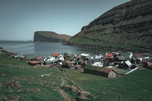 A Breathtaking view of a traditional village situated on the Faroe Islands surrounded by a stunning blue sky