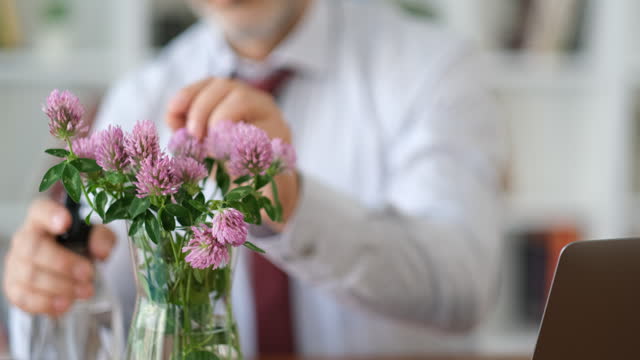 placing flowers in vase on desktop