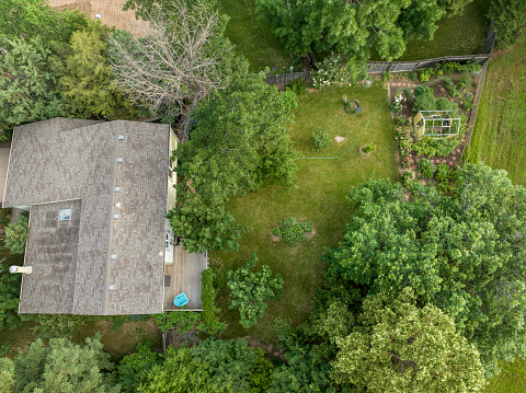 aerial view of a residential house and a green backyard with garden in summer scenery