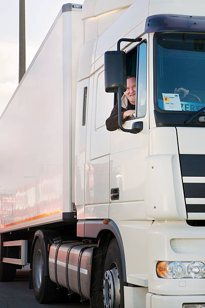 Smiling truck driver leaning out the window of his truck Truck driver and his truck - close up car transporter stock pictures, royalty-free photos & images