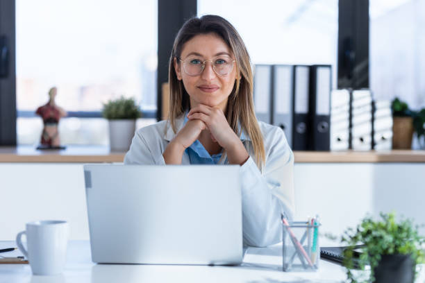 Serious female doctor working with her laptop in the medical consultation. stock photo