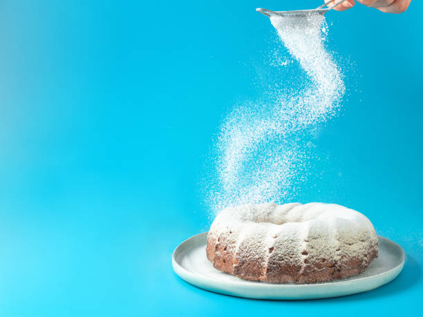 istock Female hand sprinkling icing sugar on bundt cake 1504196578