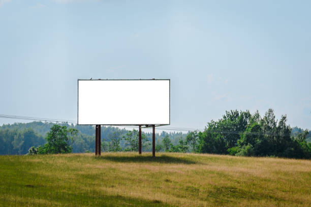 istock Billboard blank white screen for advertisement, green nature background, copy space, commercial mockup template,environment concept.Green field,forest blue sky,summer day. 1504202189