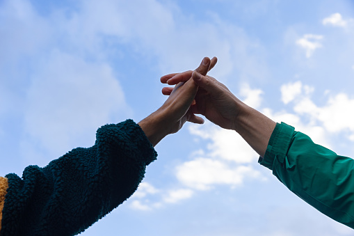 A medium, low-angle view shot of an unrecognisable multi-ethnic homosexual couple joining hands.