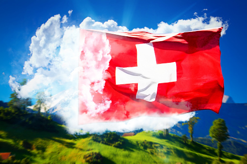 Big swiss flag on clouds and traditional mountains summer landscape background. Travel and pride concept collage.