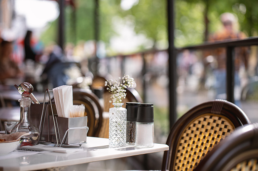 A table in a summer cafe partially served and a part of a street as background, selective focus. Restaurant, serving, summertime, location, interior, bistro, food and drink concept.