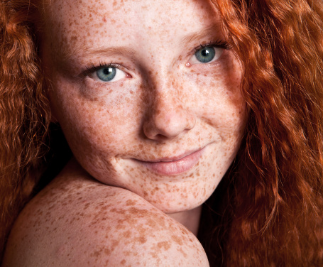 Close up of a redhead woman smiling and looking at camera.