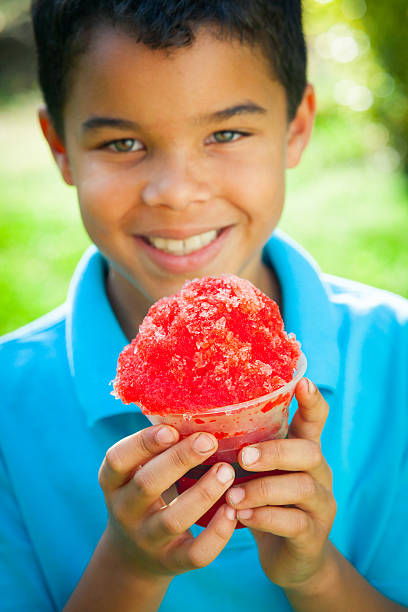 Young black boy holds snowcone outdoors.