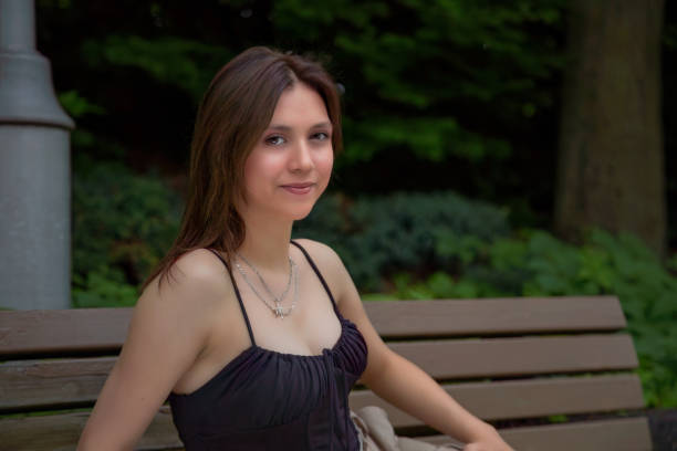 woman sitting on a bench during summer student outside college campus city lifestyle