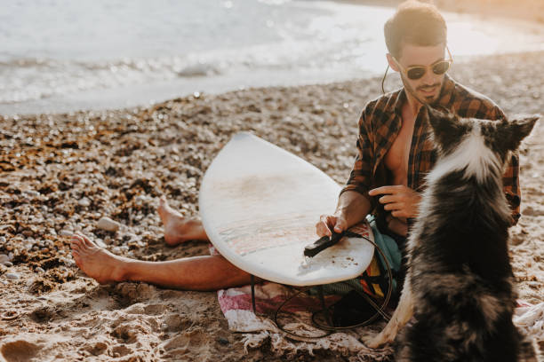 istock Handsome surfer with his dog on sandy beach 1504259712