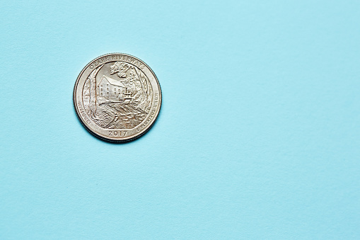 Close-up of American quarter, depicting a scene from the Ozark National Scenic Riverways in Missouri, on a textured paper background in light blue.