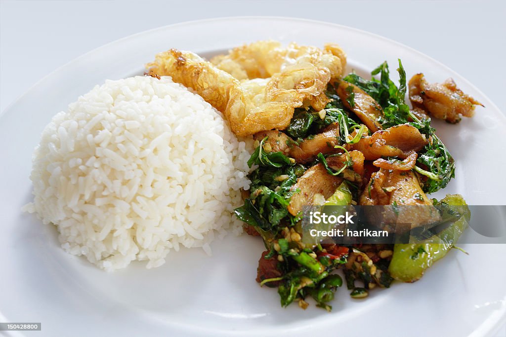 spicy stir fried chicken on rice spicy stir fried chicken on rice with fried egg Basil Stock Photo