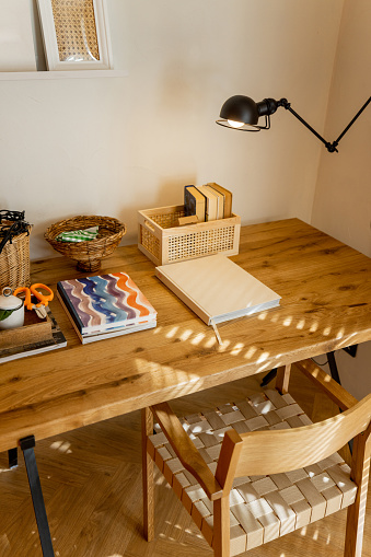 Interior view of workspace with wooden table, shelves with books and lamp in stylish studio apartement
