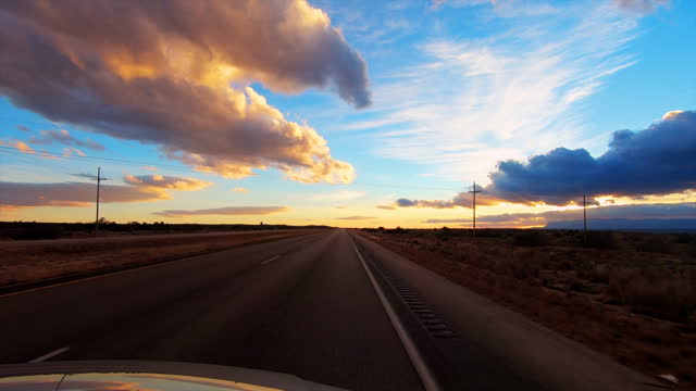 Car driving into the desert sunset: New Mexico