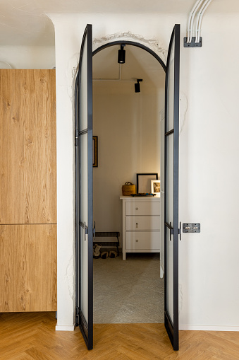 View through the metal glass door on the hallway of modern studio apartment in white tones