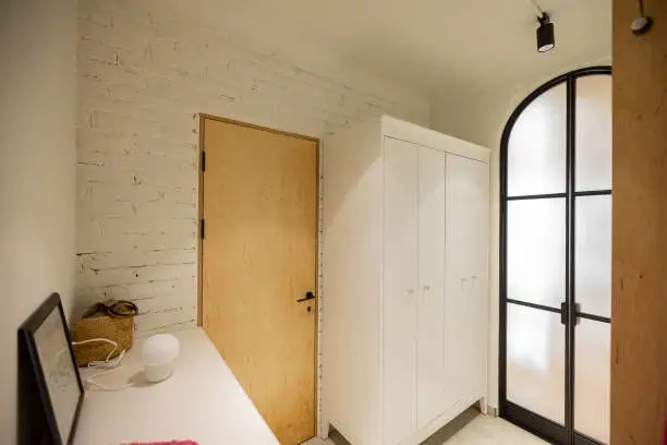 Interior of a hallway or corridor of modern apartment in white tones with arch doors