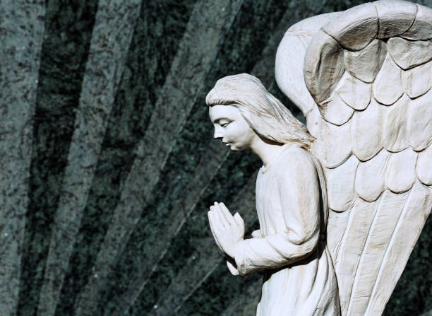 istock white angel praying with hands together on the tombstone 1504317584