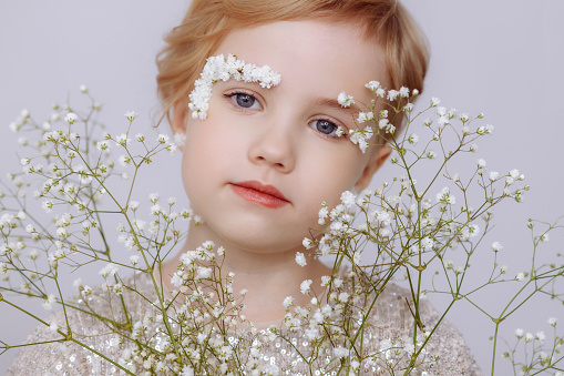 Beautiful close-up portrait of adorable little girl against the background of a blooming garden.
