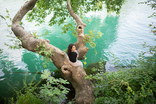 Happy woman Sitting on a Tree Branch by the river