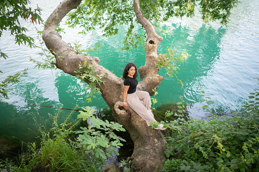 Happy woman Sitting on a Tree Branch by the river
