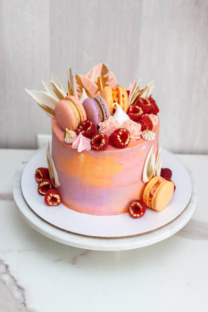 istock Pink cake decorated with fresh raspberries, chocolate petals, macaroons and meringues 1504332458