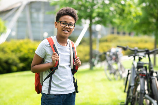 istock Schoolboy with backpack wearing white shirt standing in green park. 1504354063