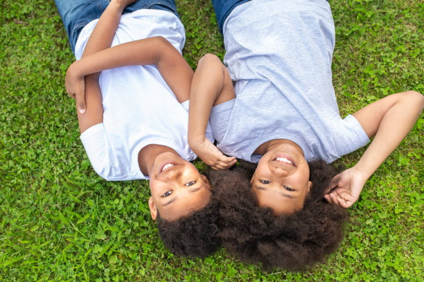 istock Little boy and girl smiling while lying on the grass in park. 1504354614